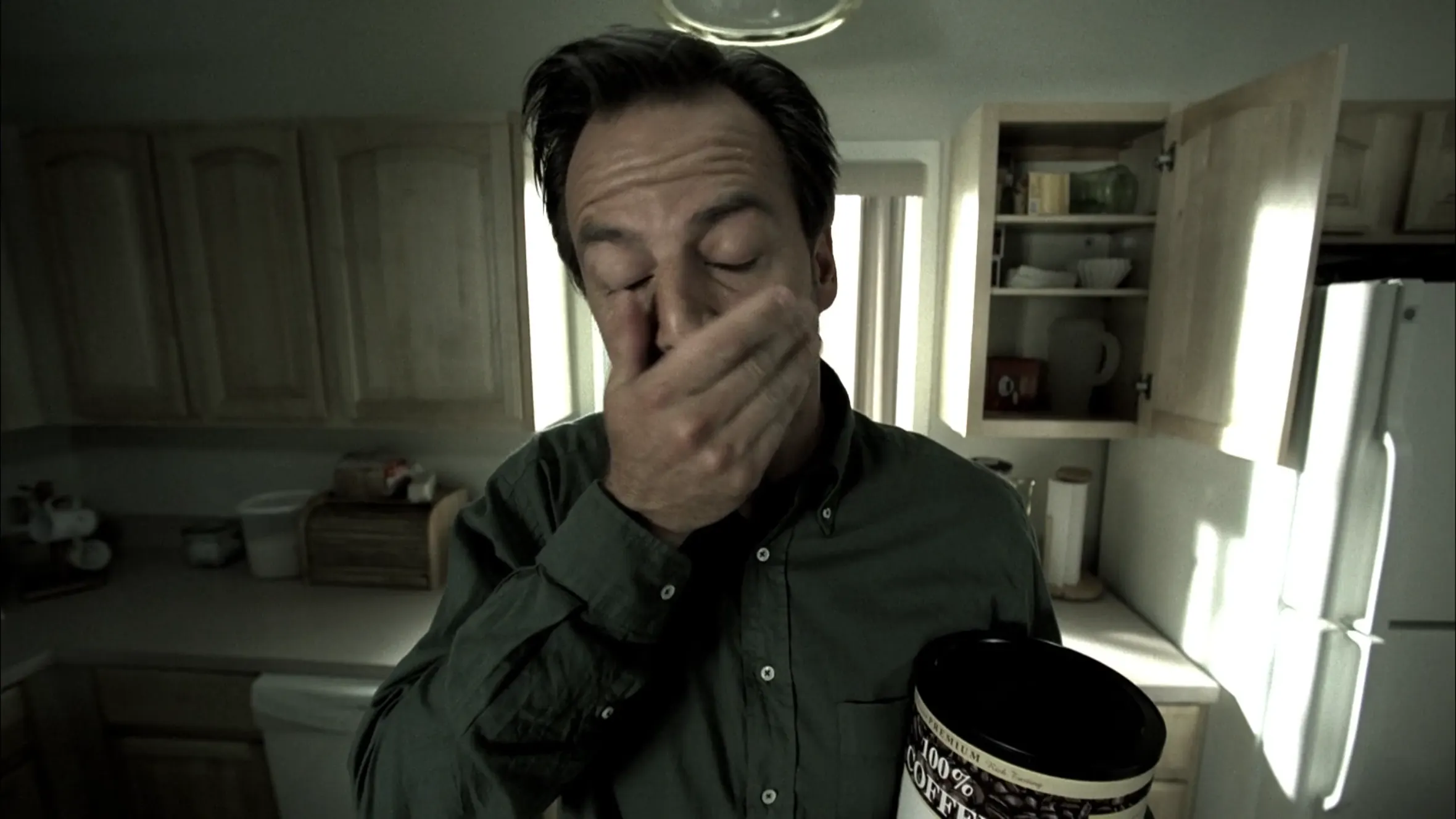 Tired man with a large jar of 100% coffee, screenshot from House S05E06 (Joy)